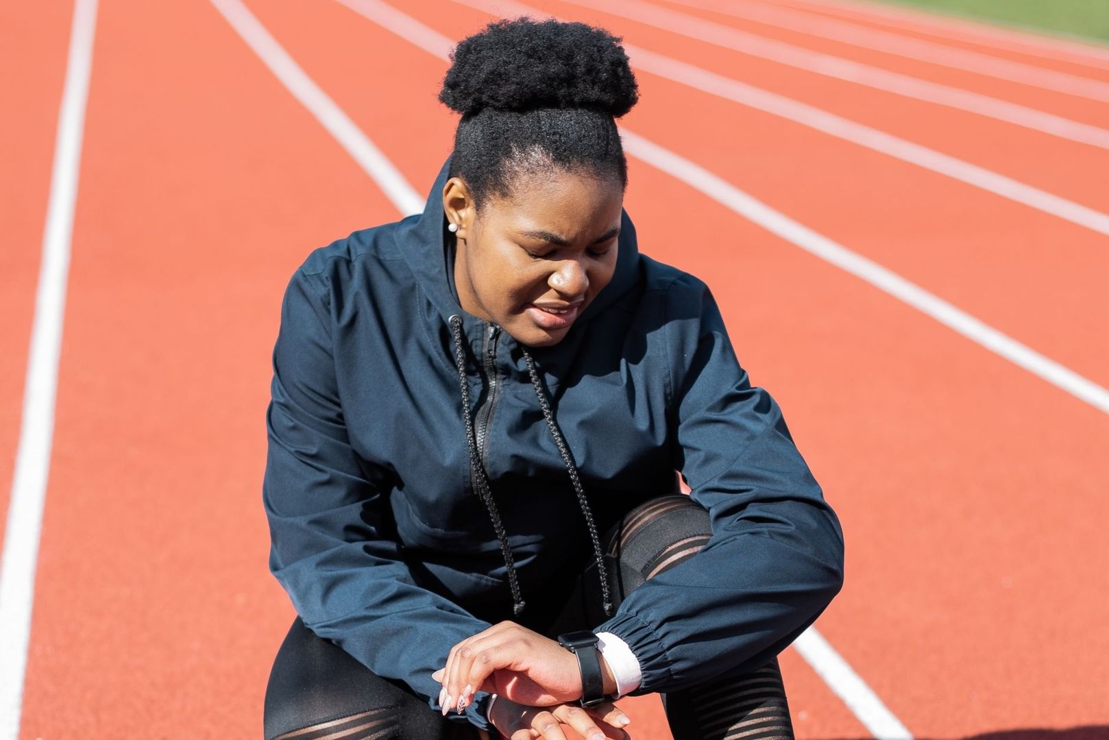 Hardloopster kijkt op haar smartwatch op een atletiekbaan