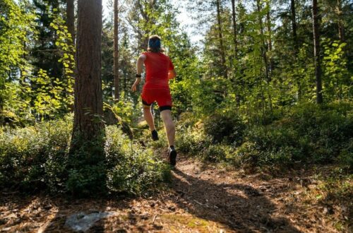 Hardloper in rood tenue loopt over een bospad tijdens een rustige duurloop