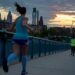 Lopers rennen over een brug bij zonsondergang, met stadsgebouwen op de achtergrond